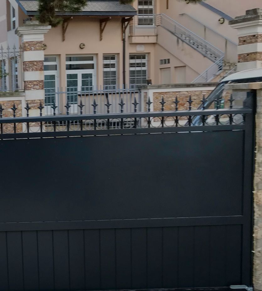Portail coulissant en aluminium anthracite à lances, entre piliers en pierre