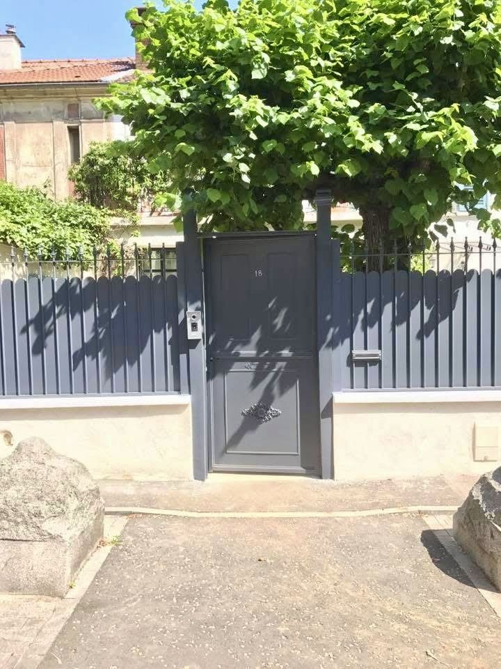 Portillon plein en aluminium anthracite dans une clôture à lames verticales